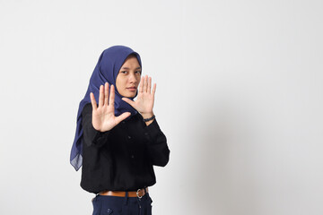 Portrait of cheerful Asian muslim woman with hijab forming a hand gesture to avoid something....