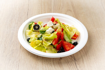 Vegetable salad with cheese. On a light wooden background.