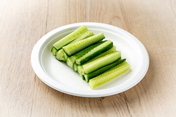 Fresh cucumbers sliced on a plate. On a light wooden background.