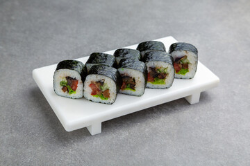 Japanese Sushi roll maki with tomato, cucumber, mushrooms on a white stand, gray background
