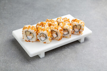 Japanese Sushi roll in fried onion with shrimp on a white stand, gray background © TrapezaStudio