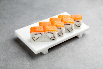 Japanese Sushi roll Philadelphia light with eel on a white stand, gray background