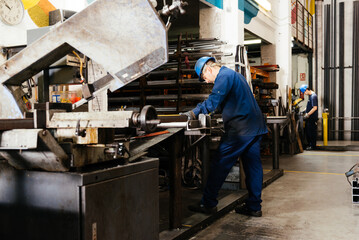 Male factory workers operating machinery in warehouse