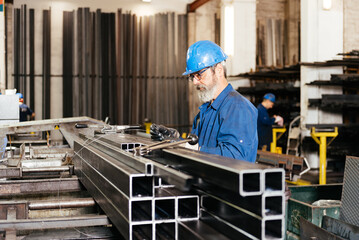 Naklejka na ściany i meble Man worker tying up metal beams in construction workshop at factory