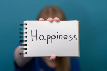 Kobieta trzyma w dłoni z napisanym słowem szczęście w języku angielskim