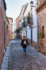 Fototapeta na wymiar Tourist woman strolling quietly through the narrow streets of the city of Caceres.