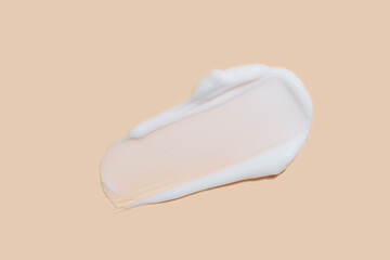 Face cream smear on beige background. White lotion swatch. Abstract cosmetic cream texture. skin care beauty background