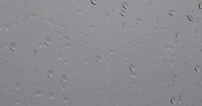 A raindrops on a window, with a view of a cloudy sky. pano