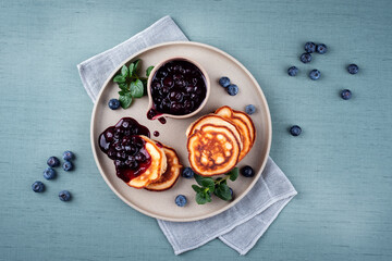 Traditionelle amerikanische Pfannkuchen mit Blaubeeren Früchte und Marmelade serviert als Draufsicht auf einem Nordic Design Teller 
