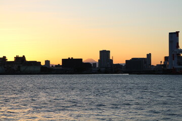 Mount Fuji over modern buildings in dusk viewed from Tokyo Bay, Japan