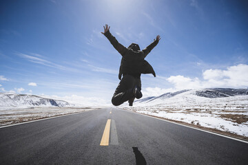 Asian woman jumping on high altitude country road