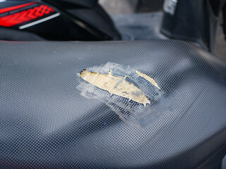 The motorbike seat has holes and the foam inside is visible from the outside