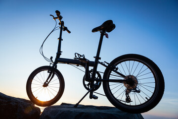Fototapeta premium A folding bike on sunrise seaside rock