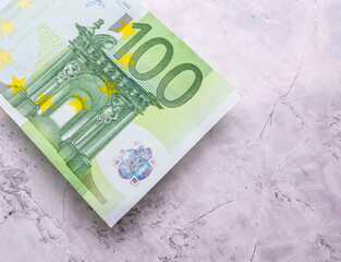 Close-up high quality photo of a 100 Euro bill lying on a marble background. Euro banknotes, inflation and price increases. Savings and investment. Earning money.