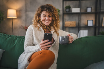 One woman with curly hair at home use mobile phone smartphone sms texting or browse internet