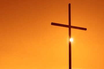 Silhouettes of crucifix symbol on top mountain with bright sunbeam on tyellow, orange sky...
