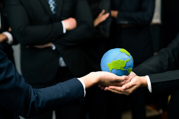 Top view business people holding Earth together in synergy as team building to utilize eco...