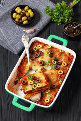 lasagna with olive rings in green baking dish