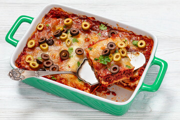 lasagna with olive rings in green baking dish