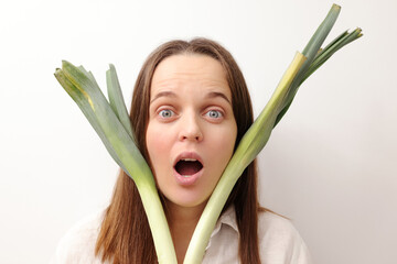 Shocked surprised astonished Caucasian woman holding green leek studying about balanced nutrition...