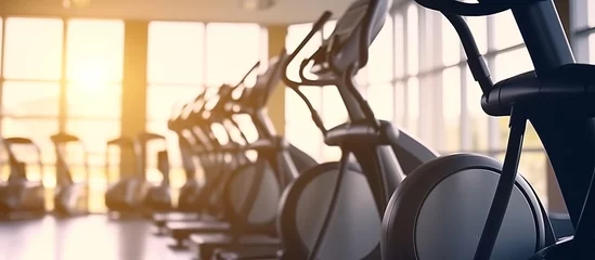 Fotobehang Elliptical in Modern gym interior with equipment. Row of training exercise bikes wheel detail © Dzikir