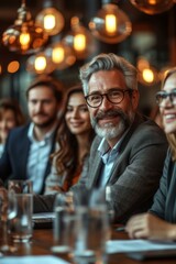 A group of business professionals sitting around a table and smiling at the camera