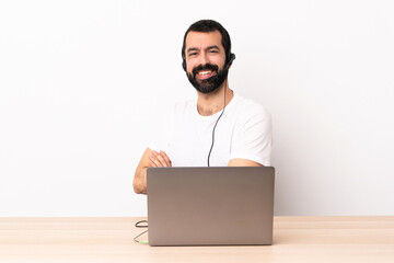 Telemarketer caucasian man working with a headset and with laptop with arms crossed and looking forward.