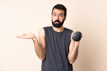 Caucasian sport man with beard making weightlifting over isolated background having doubts