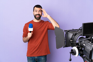 Reporter man holding a microphone and reporting news over isolated purple background with surprise...