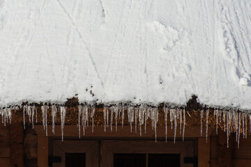 End of winter. The icicles are melting from house roof. Thaw and ice melting.