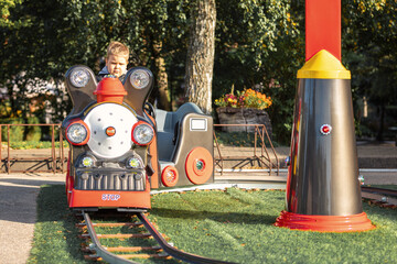 Happy child boy having fun in park. Taking a ride on child train.