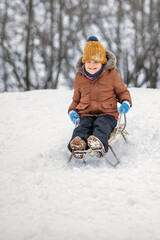 Fototapeta na wymiar Happy Child sledding down a snowy hill. Winter vacation concept