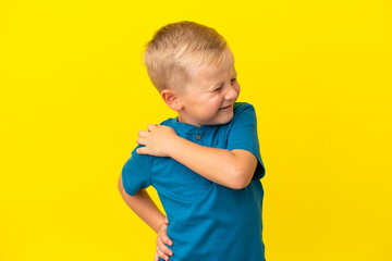 Little Russian boy isolated on yellow background suffering from pain in shoulder for having made an...
