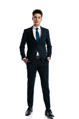 elegant young businessman in navy blue suit holding hands in pockets