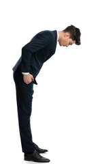 side view of elegant man in navy blue suit with hands in pockets looking down