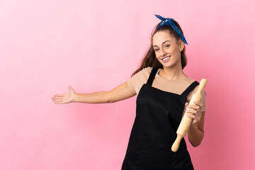 Young woman holding a rolling pin extending hands to the side for inviting to come