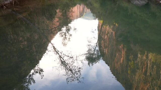 Turia river surface with flowing water with cliffs and trees reflected