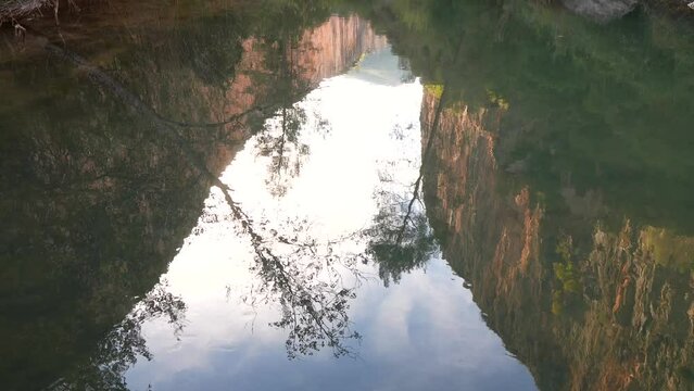 slow motion of Tajo river surface with flowing water with cliffs and trees reflected