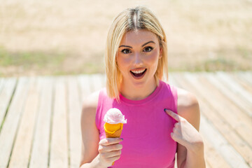 Young pretty blonde woman with a cornet ice cream at outdoors with surprise facial expression