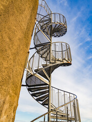 Spiral Staircase Against Blue Sky Alongside Beige Building Facade