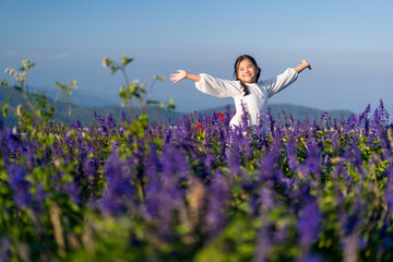 Asian child or kid girl standing on beauty of many fresh flowers to happy smile on beautiful blue violet in nature flower field garden on holiday travel and mountain sky view at Yingyong flower garden