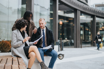 Fototapeta premium Three professional colleagues in a casual business meeting outside. They are discussing papers, engaging in a productive conversation.