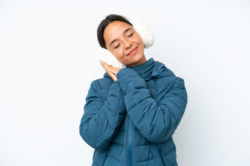 Young hispanic woman wearing a winter earmuffs isolated on white background making sleep gesture in...