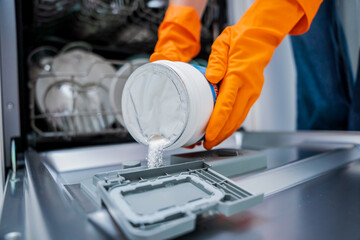 Woman adding detergent to dishwasher machine drawer