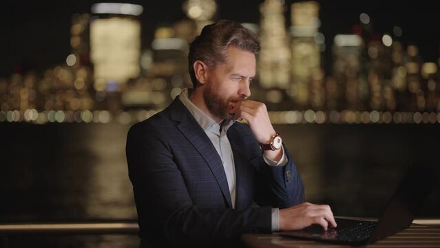 Business man working on laptop at night with neon street lights in New York City. Businessman in night Ney York. Businessman using tablet laptop outdoor. Business success in night city.