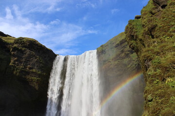 Iceland waterfall green grass and rainbow