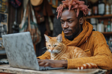 Young man working on a laptop at home, accompanied by his cute grey cat, blending business with the comfort of domestic life.