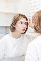 Young beautiful woman looking at mirror and confusing because of new wrinkles	