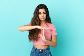 Young caucasian woman isolated on blue background making time out gesture