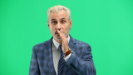 A man, close-up, on a green background, tells a secret